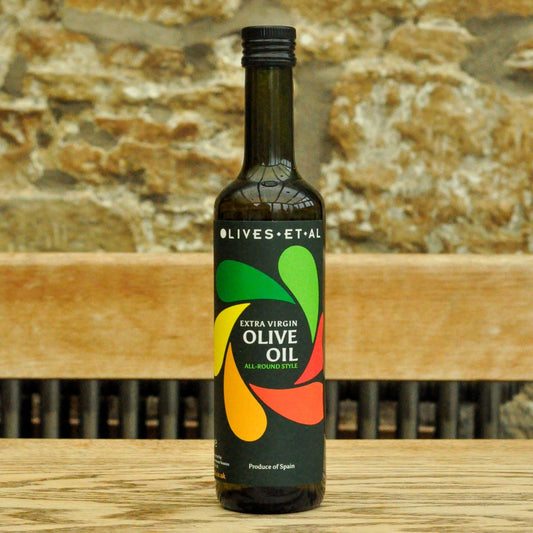 Bottle of olive oil with colorful label on a wooden surface and stone wall background