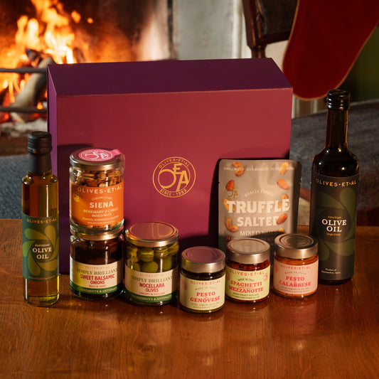 Olives Et Al Italian Kitchen Hamper in a purple gift box, featuring House Extra Virgin Olive Oil, Basil Olive Oil, Pesto alla Genovese, Pesto alla Calabrese and Spaghetti Mezzanotte. Also included are Nocellara del Belice olives, balsamic onions, Siena Rosemary & Chilli Nuts and truffle salted roasted nuts. With bottles, jars, pasta and savoury snacks, this Italian-inspired collection makes a lovely Christmas gift for food lovers, ideal for festive starters, pasta suppers and sharing at the Christmas table.