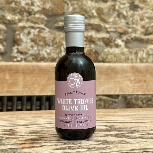 Bottle of white truffle olive oil with a pink label on a wooden surface.