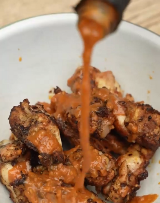 Close-up of chicken wings glazed with sticky Chipotle Hot Sauce, showing charred edges