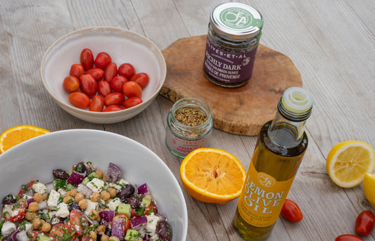 Fresh Greek salad with chickpeas, cucumber, tomatoes, red onion, feta, and olives in a white bowl