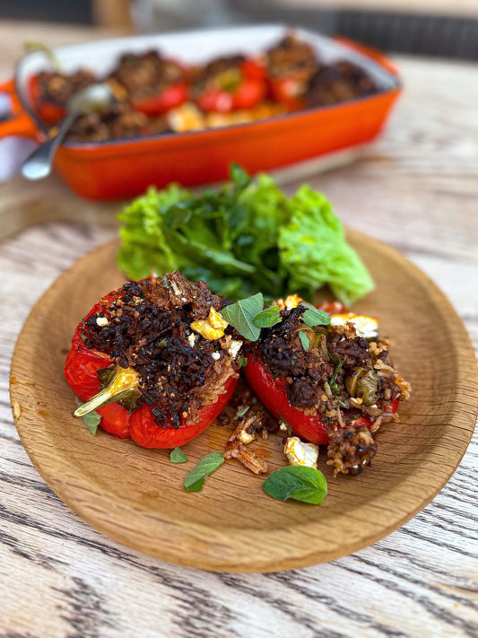 Baked bell peppers stuffed with Adana-spiced ground lamb, topped with herbs on a rustic plate