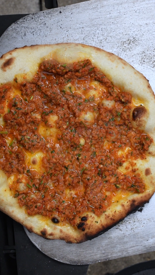 Lahmacun flatbread topped with spiced lamb, harissa and red pepper paste baked until crisp.