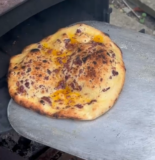 Flatbreads in the oven – “Moroccan tapenade and chilli oil flatbreads baking in a woodfired oven, edges blistering and golden.”