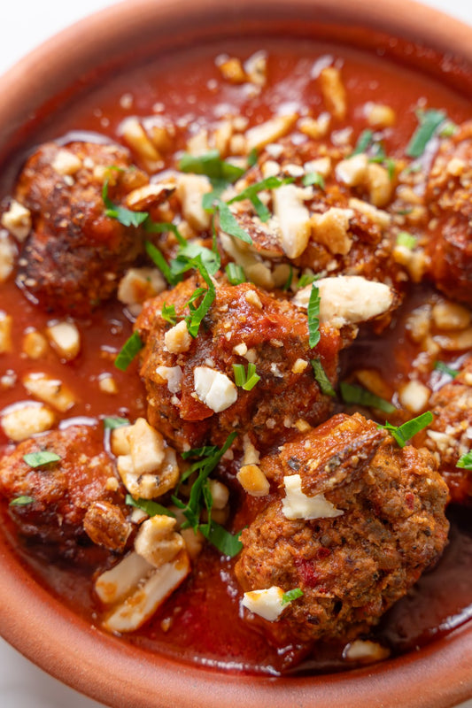 Adana meatballs in harissa tomato sauce topped with crushed spiced nuts and parsley.