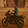 Person on a motorcycle in a desert landscape with large rock formations.