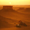 Desert landscape with a sunset and a vehicle in the foreground