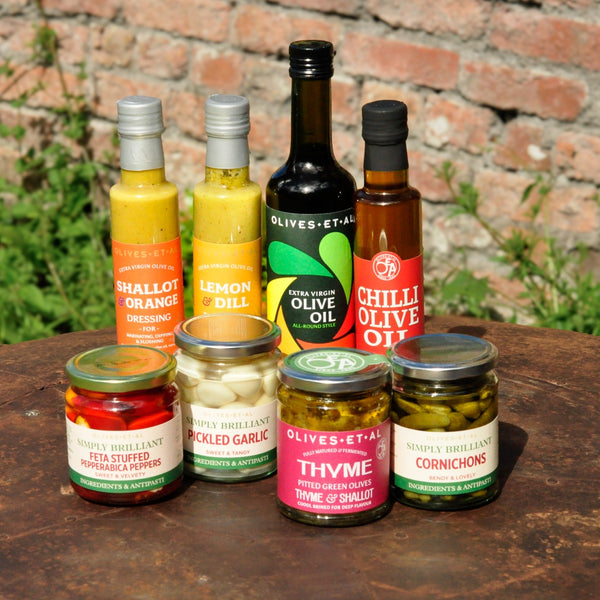 Assorted condiments including bottles and jars on a wooden surface with a brick wall background.
