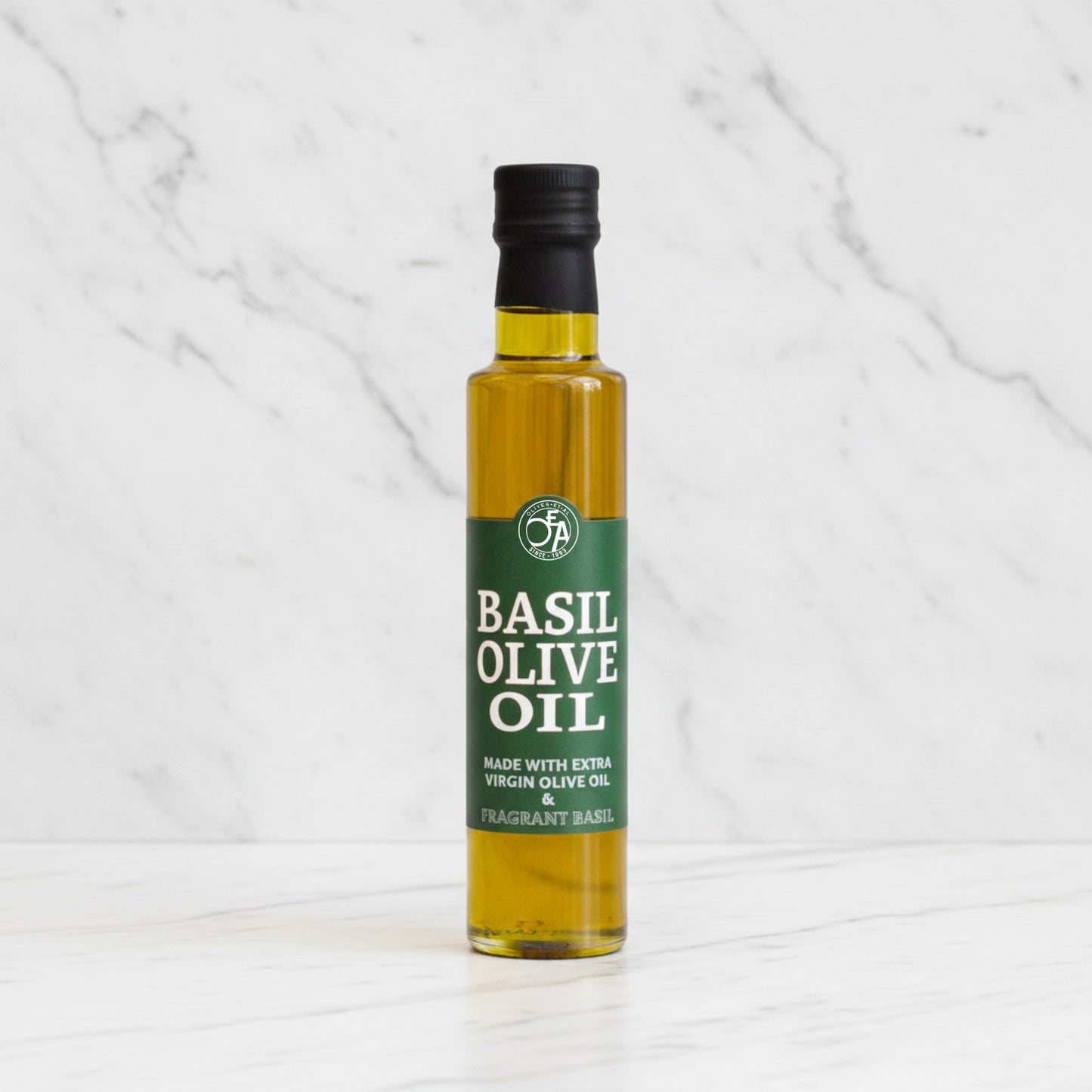 Bottle of basil olive oil on a white marble background