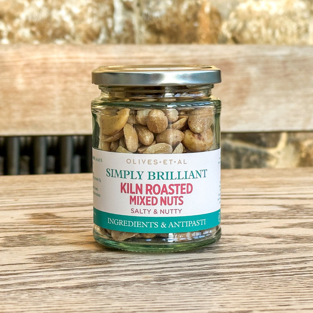Jar of kiln roasted mixed nuts with a label on a wooden surface
