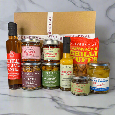 Collection of various chili and olive oil products on a marble surface with a branded box.