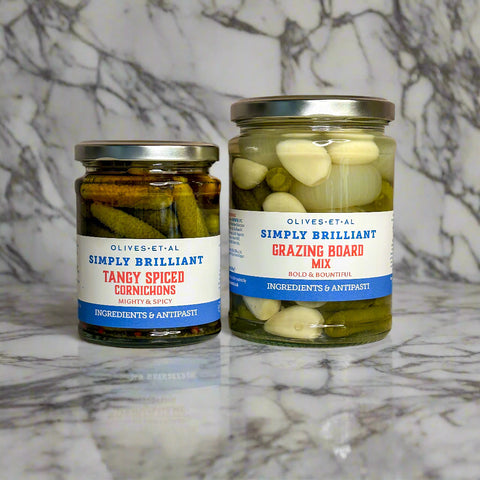 Two jars of pickled vegetables on a marble surface
