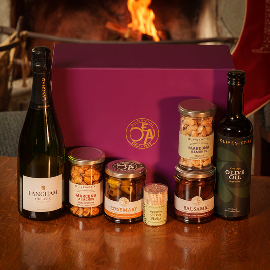 Olives Et Al Dorset Aperitivo Hamper presented in a purple gift box, featuring a bottle of Langham Culver Classic Cuvée sparkling wine, House Extra Virgin Olive Oil, jars of Balsamic and Rosemary Olives, Lightly Salted Marcona Almonds, Sweet Paprika Marcona Almonds and Signature Olive Picks. A thoughtful Christmas gift for food and wine lovers, combining Dorset sparkling wine with savoury Mediterranean treats, perfect for festive aperitifs, Christmas Eve nibbles and sharing with family and closest friends.