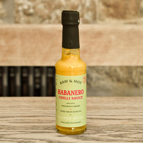 Bottle of Raw & Hot Habanero Chilli Sauce on a wooden background