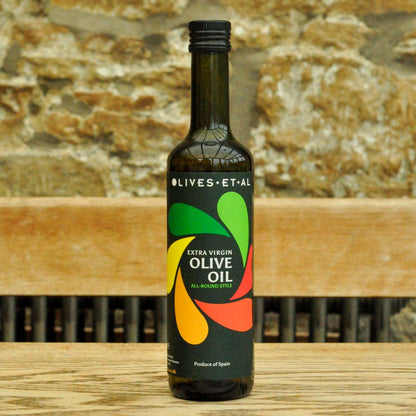 Bottle of olive oil with colorful label on a wooden surface and stone wall background