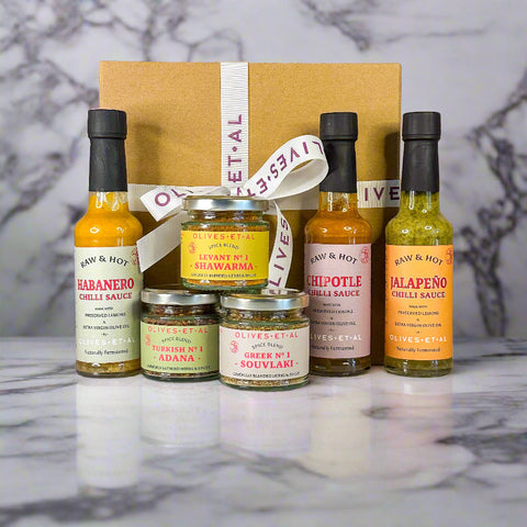 Collection of hot sauce bottles and jars with visible brand names on a neutral background
