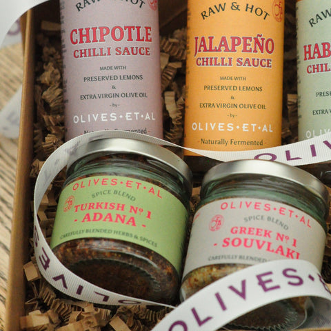 Assorted chili sauces and spice blends in a box with visible branding.
