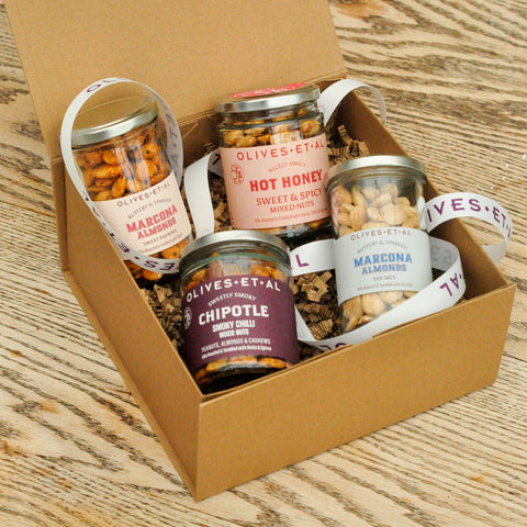 Box of Olives Et Al snack jars on a wooden surface