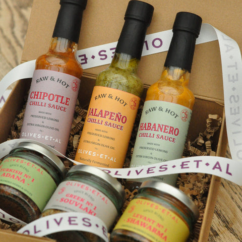 Assorted hot chili sauces and olives in a gift box with visible branding.