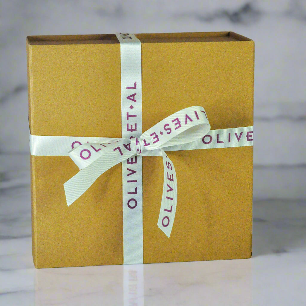 Brown gift box with a white ribbon and 'OLIVES' branding on a textured surface.