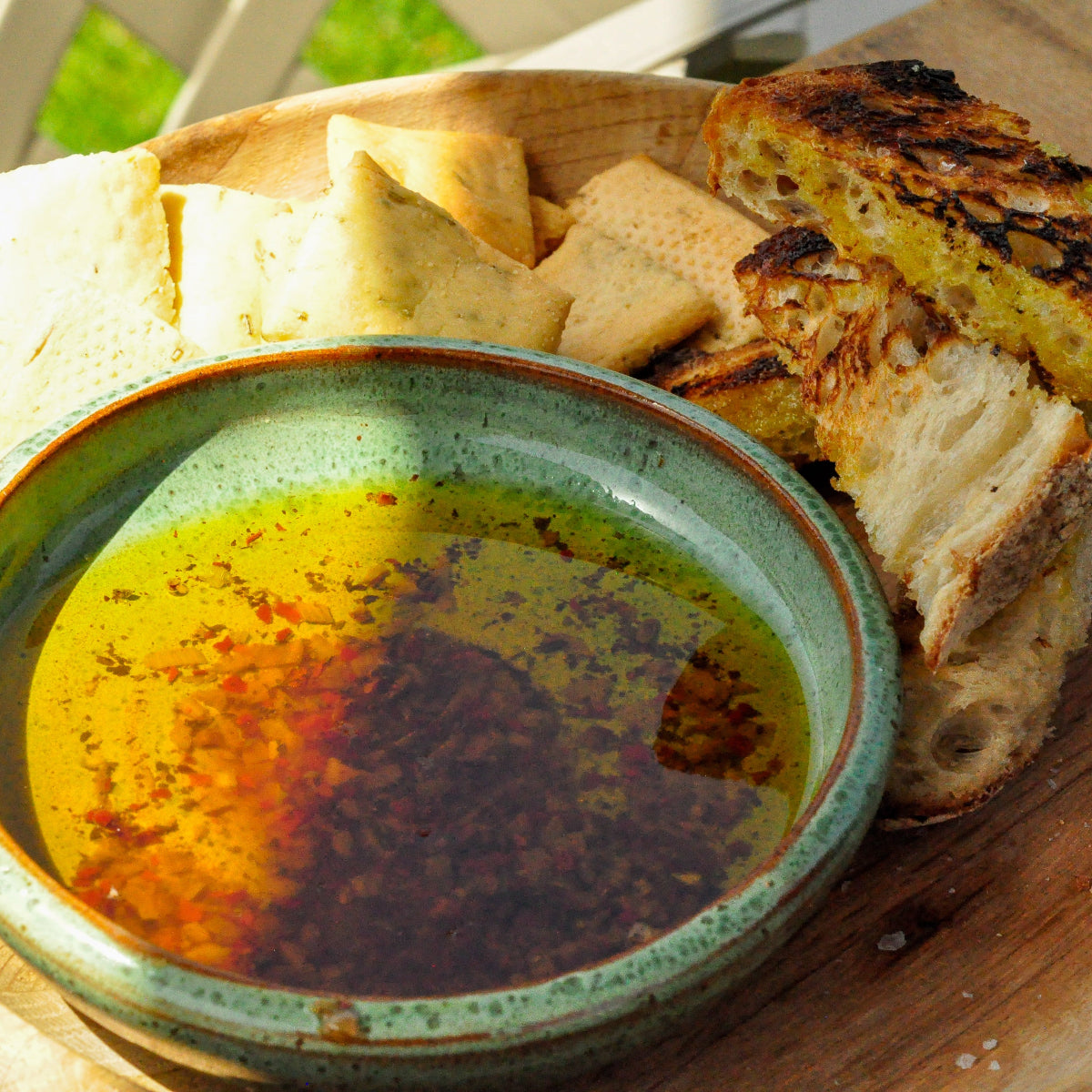 Bread and grilled cheese on a wooden plate with a bowl of butter