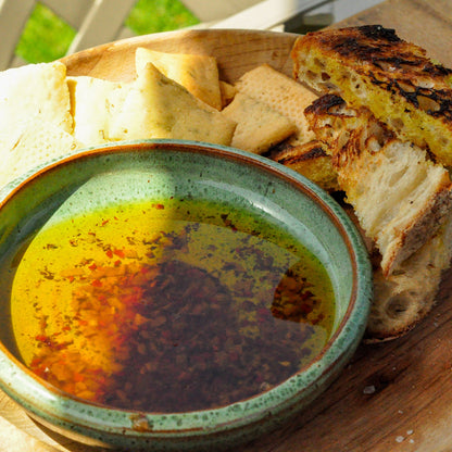 Bread and grilled cheese on a wooden plate with a bowl of butter