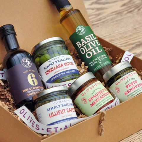 Assorted olive oil and olive products in a box on a wooden surface