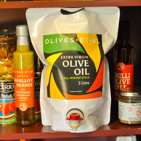 Bag of extra virgin olive oil on a shelf with other olive products.