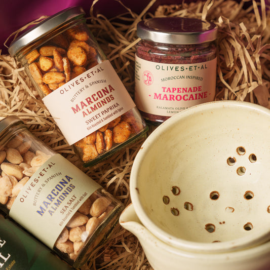 Olives Et Al Long Table Hamper in a large purple gift box, featuring a cream hand-thrown Olive Bowl, House Extra Virgin, Basil and Lemon Olive Oils, and jars of Barbary, Aleppo, Balsamic and Rosemary Olives. Also includes Tapenade Marocaine, lightly salted and sweet paprika Marcona almonds, truffle salted roasted nuts, Rosemary & Sea Salt Regañas crackers and olive picks. A generous Christmas gift for food lovers, ideal for festive grazing, dipping bread and sharing tasty nibbles around the Christmas table.