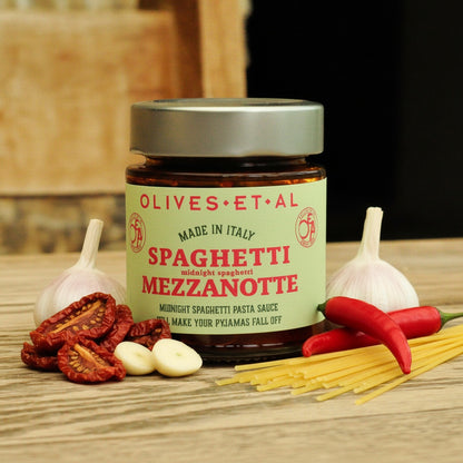 Jar of Olives Et Al Spaghetti Mezzanotte with ingredients on a wooden surface