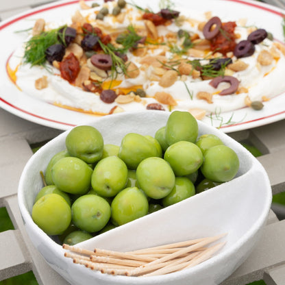 Bowl of Nocellara olives with a plate of labneh in the background