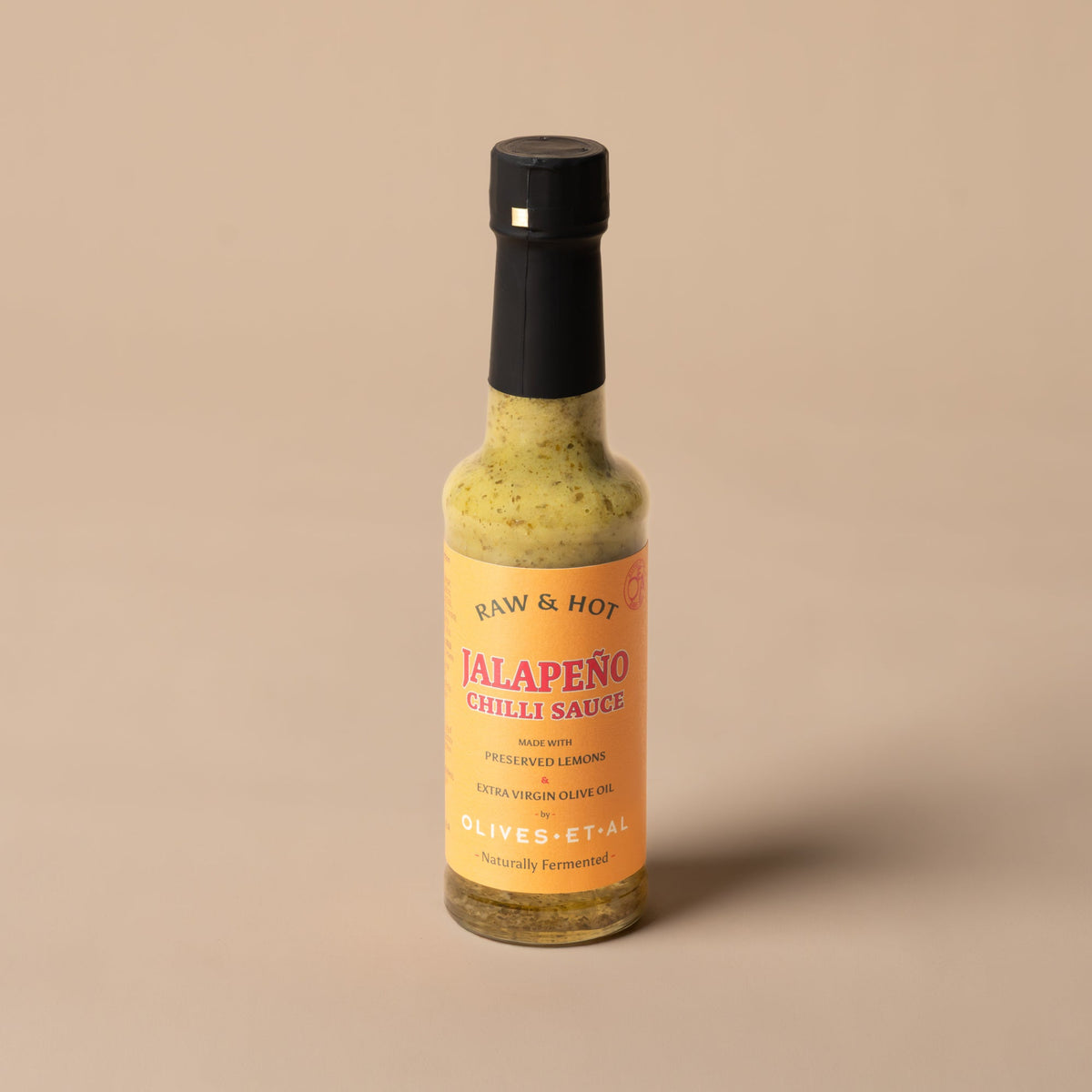 Bottle of Raw & Hot Jalapeño Chilli Sauce on white marble