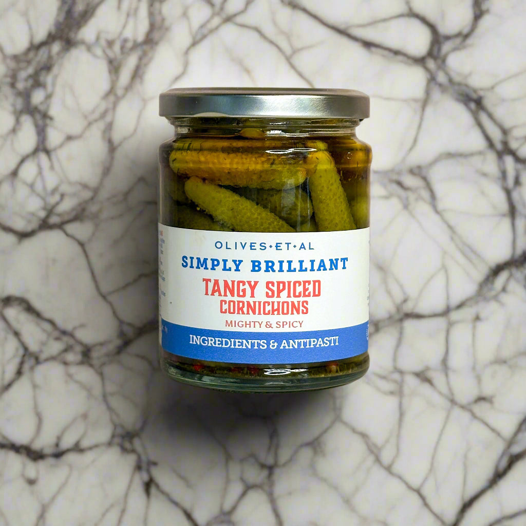 Jar of tangy spiced cornichons on a marble surface