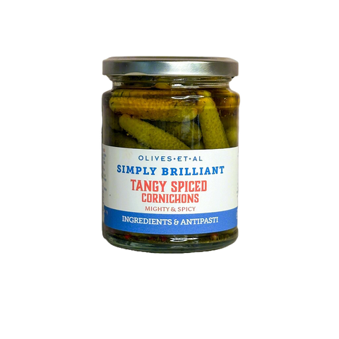 Jar of tangy spiced cornichons with a label on a white background