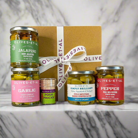 Collection of Olives-et-Al jars with a decorative ribbon on a marble surface.