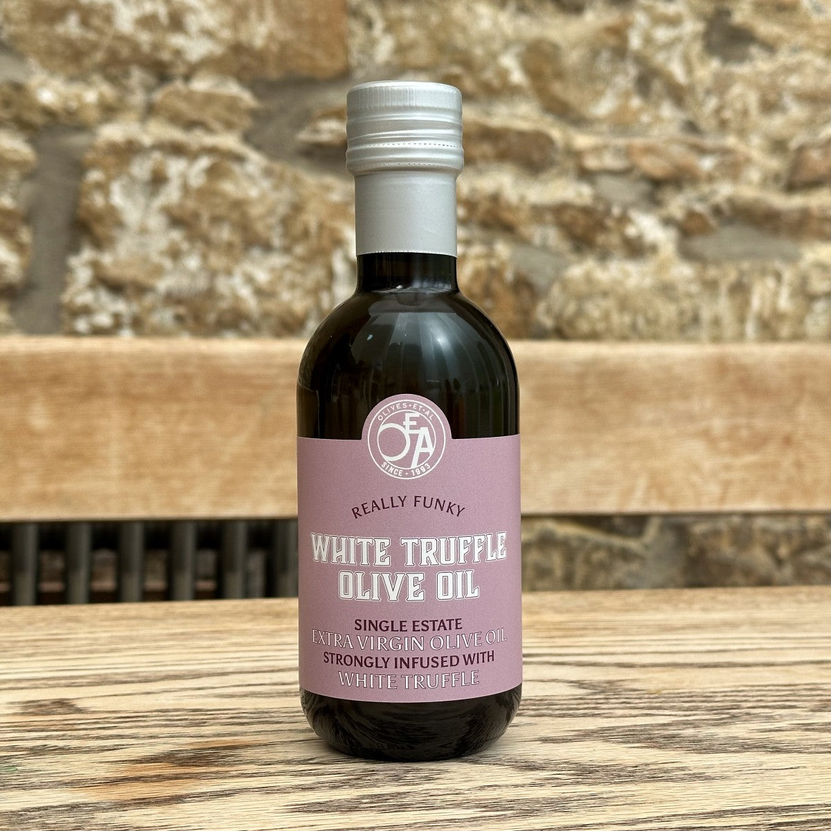 Bottle of white truffle olive oil with a pink label on a wooden surface.