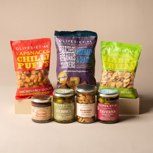Olives Et Al While the BBQ Heats Up Bundle featuring eight savoury snacks and accompaniments for sharing before grilling. The selection includes Chipotle Smoky Chilli Nuts, Sweet Paprika Marcona Almonds and rich Tapenade Marocaine, alongside Taverna Mixed Pitted Olives in Extra Virgin Olive Oil and fragrant Fennel and Orange Pitted Mixed Olives. Crisp Rosemary and Sea Salt Regañas Crackers provide a crunchy pairing for the tapenade and olives.