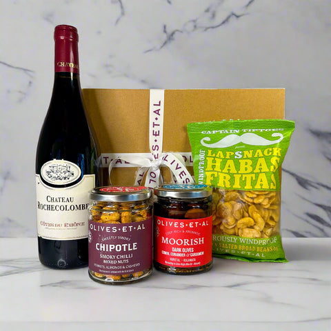 Wine bottle, snack pack, and jars on a surface with a neutral background