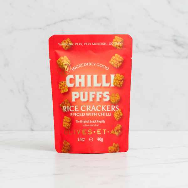 Red 40g pouch of Olives Et Al Chilli Puffs on white marble