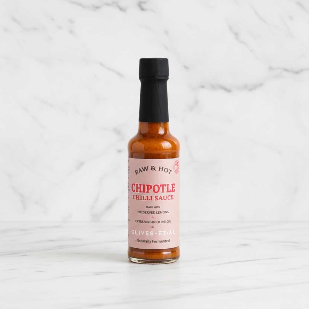 Bottle of chipotle chili sauce on a white marble background