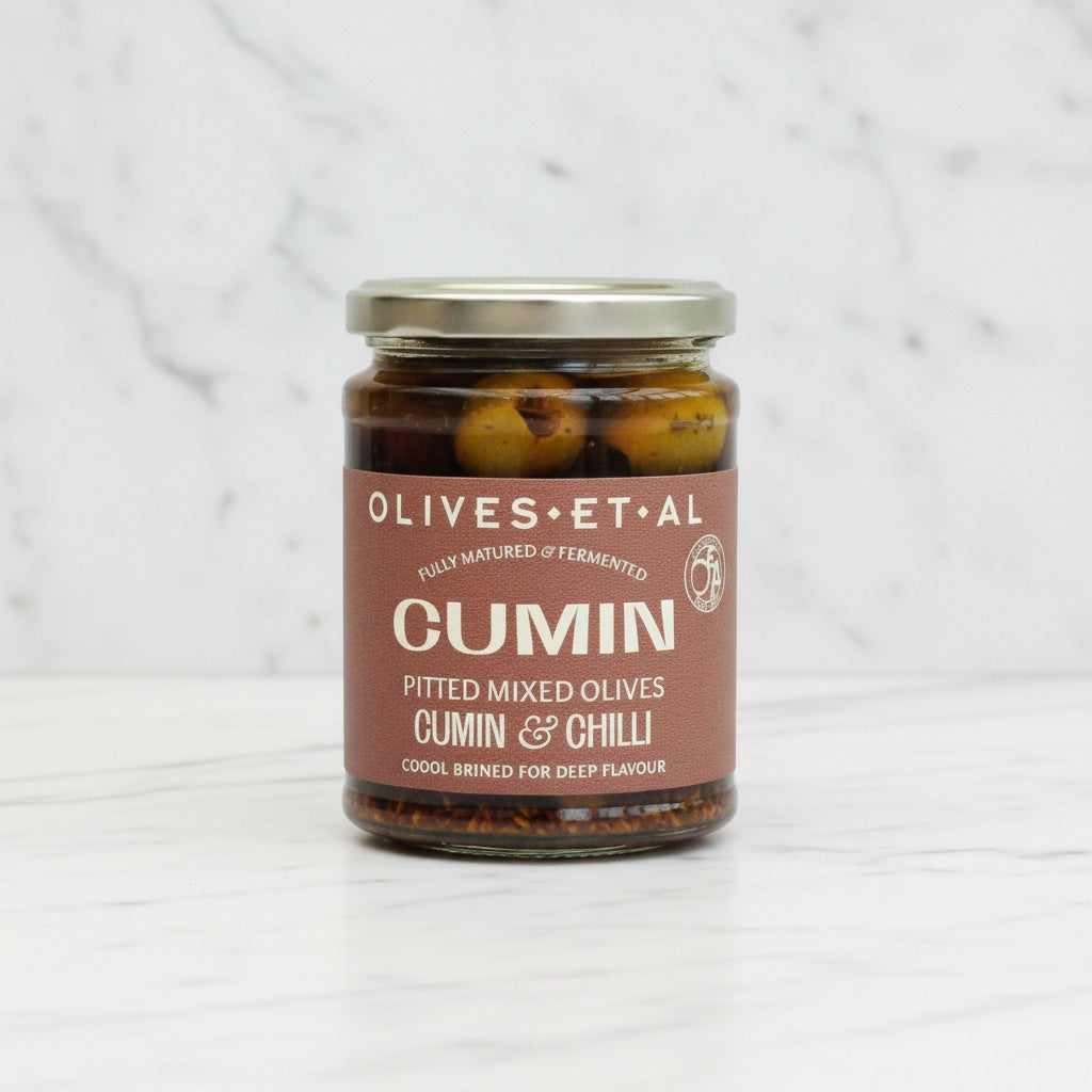 cumin pitted mixed olives on a white marble backdrop