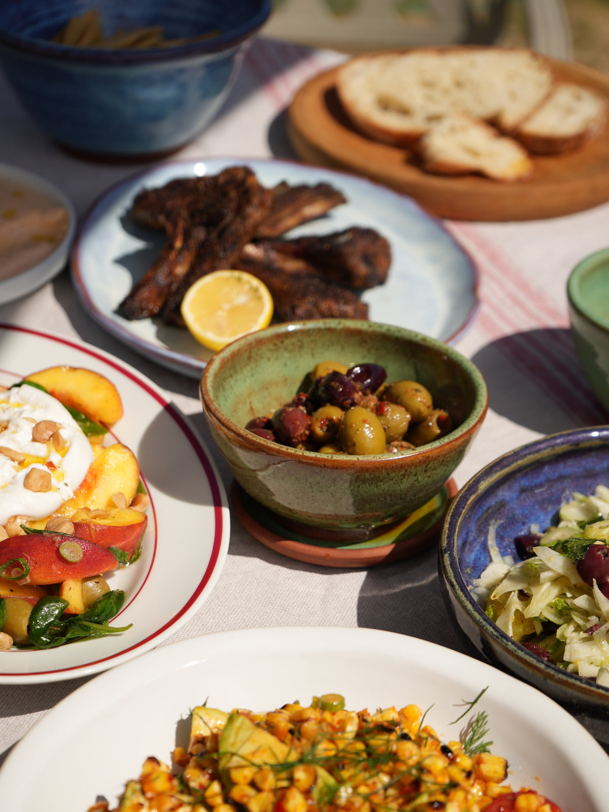 Olive bowl with grilled meat, salads and bread on a sharing table