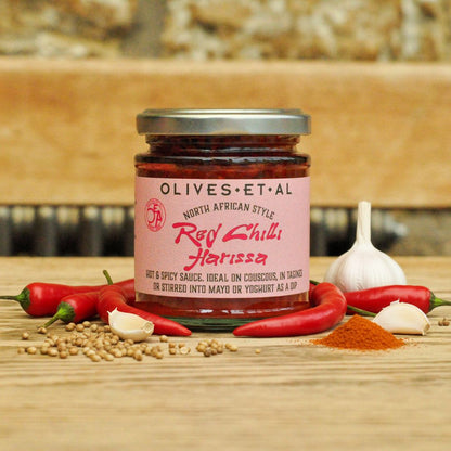 Olives Et Al red Chilli Harissa with fresh chillies, garlic and spices on a wooden surface