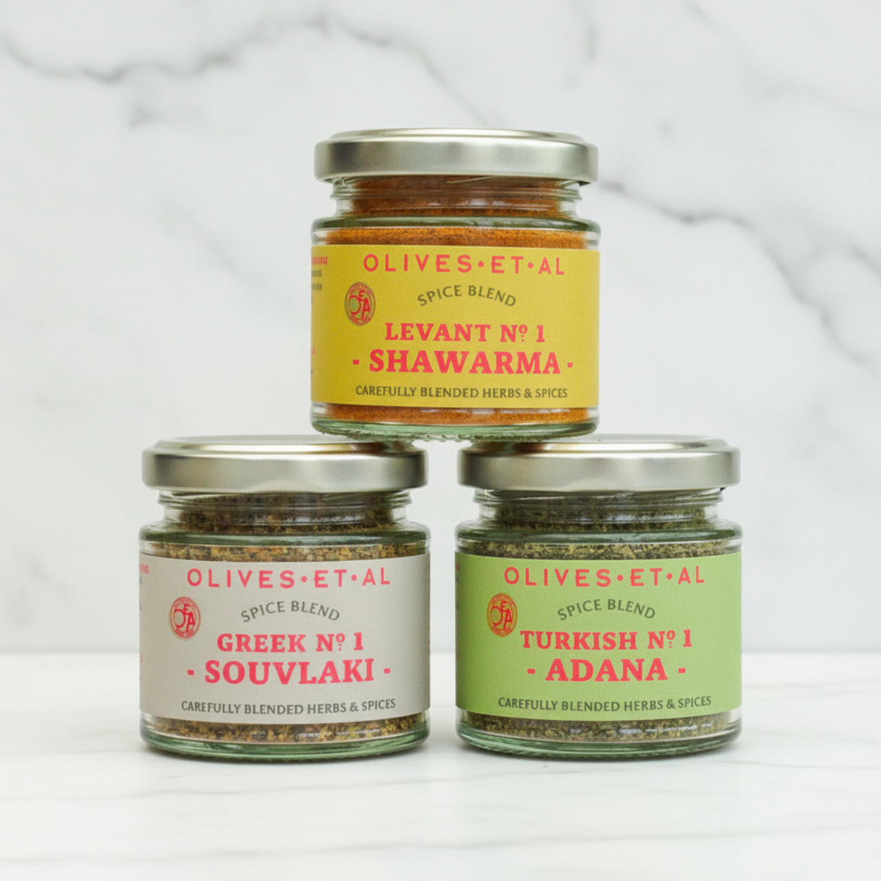 a trio of spice blends in jars of white marble background